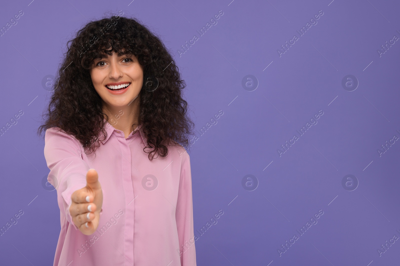 Photo of Happy young woman welcoming and offering handshake on violet background, space for text