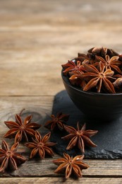 Photo of Aromatic anise stars with bowl on wooden table