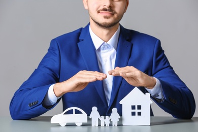 Photo of Male insurance agent covering paper family, car and home at table, closeup