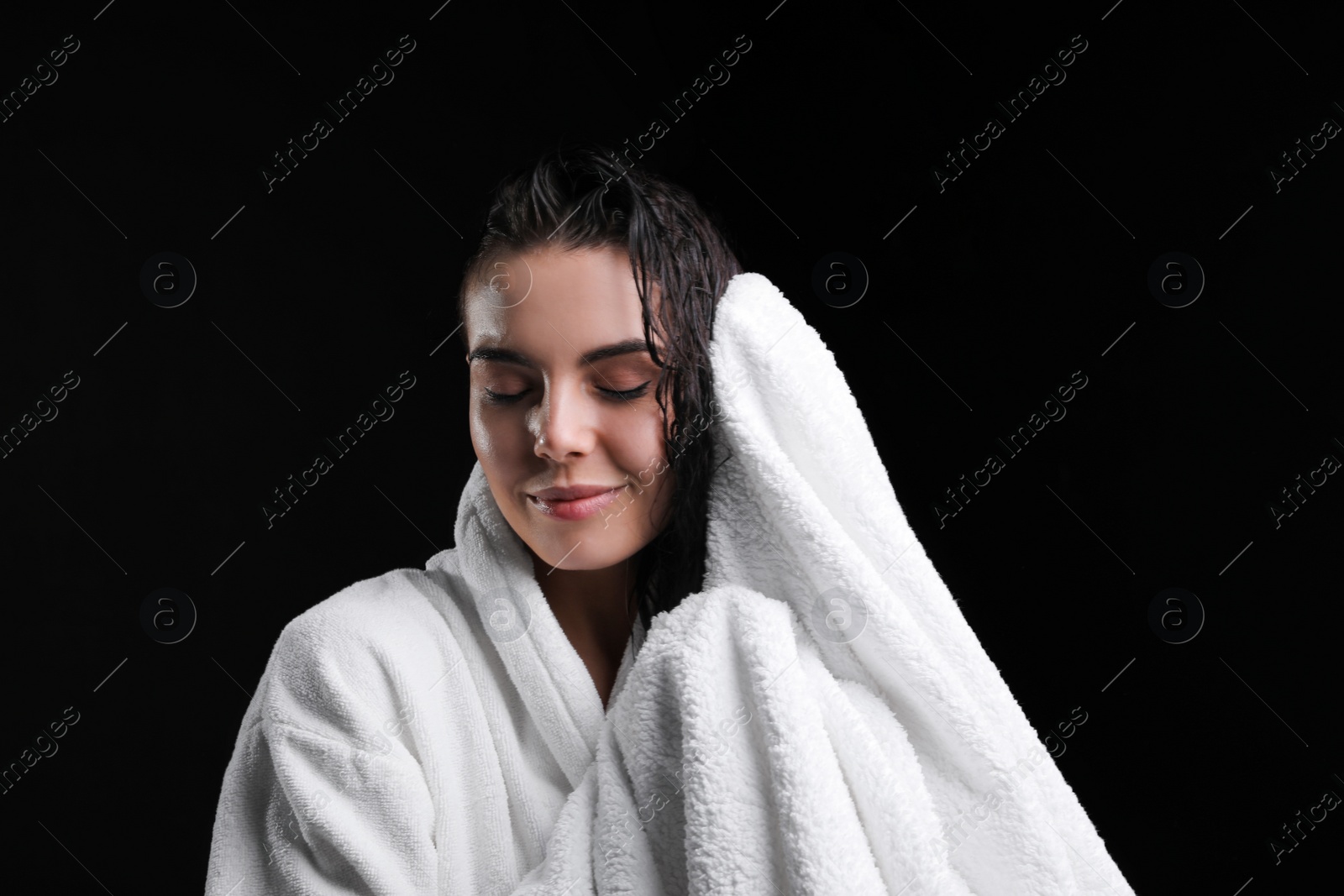 Photo of Pretty woman drying hair with towel after washing on black background