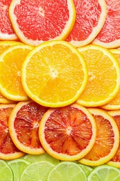 Photo of Slices of fresh citrus fruits as background, top view