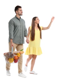 Photo of Young couple with shopping basket full of products isolated on white