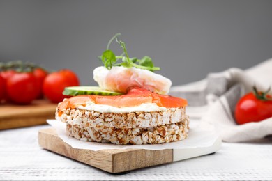 Photo of Crunchy buckwheat cakes with salmon, poached egg and cucumber slices on white wooden table