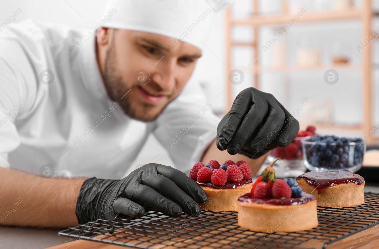 Photo of Male pastry chef preparing desserts at table in kitchen