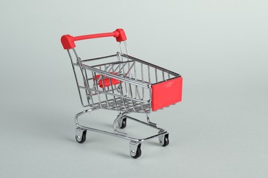 Small metal shopping cart on light background