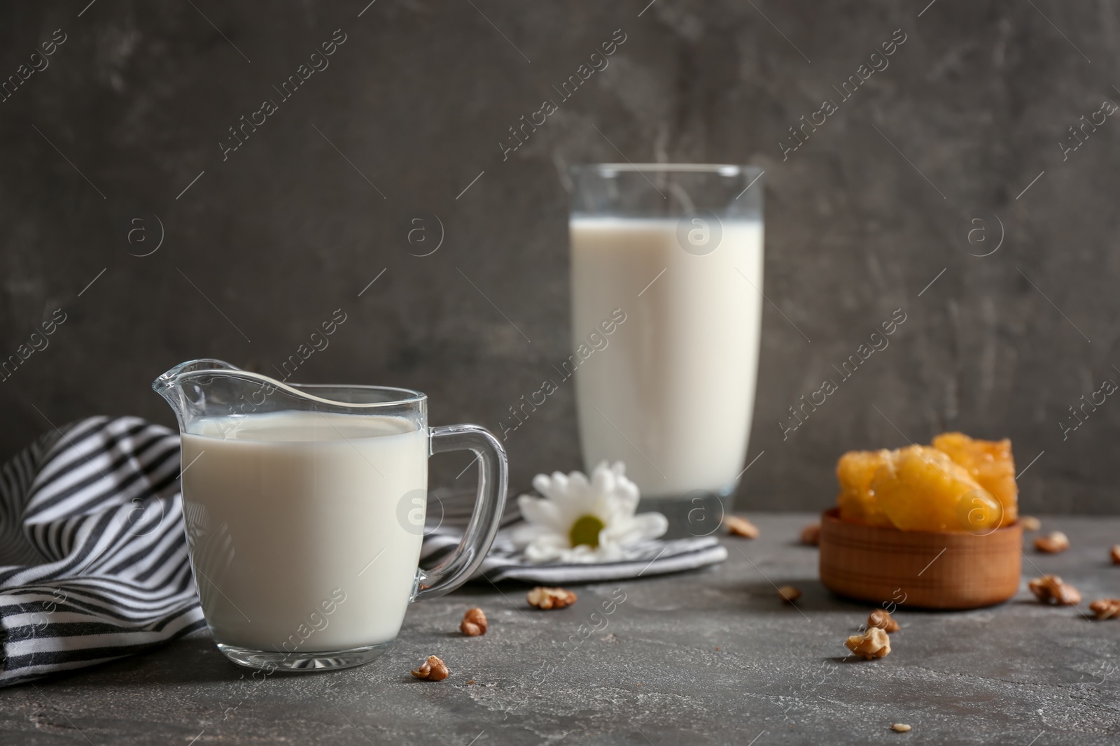 Photo of Jug with milk and nuts on grey table