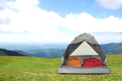 Image of Camping tent with sleeping bags in mountains on sunny day