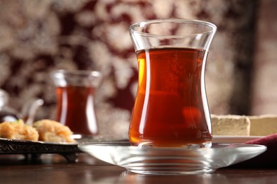 Photo of Traditional Turkish tea in glass on wooden table, closeup. Space for text