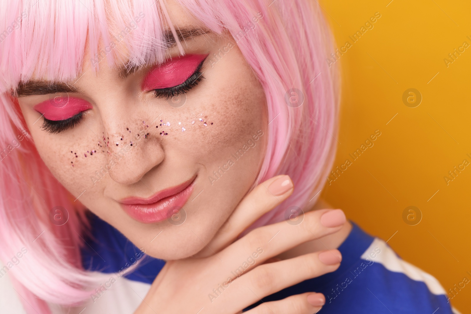 Photo of Beautiful woman with bright makeup and glitter freckles on yellow background, closeup