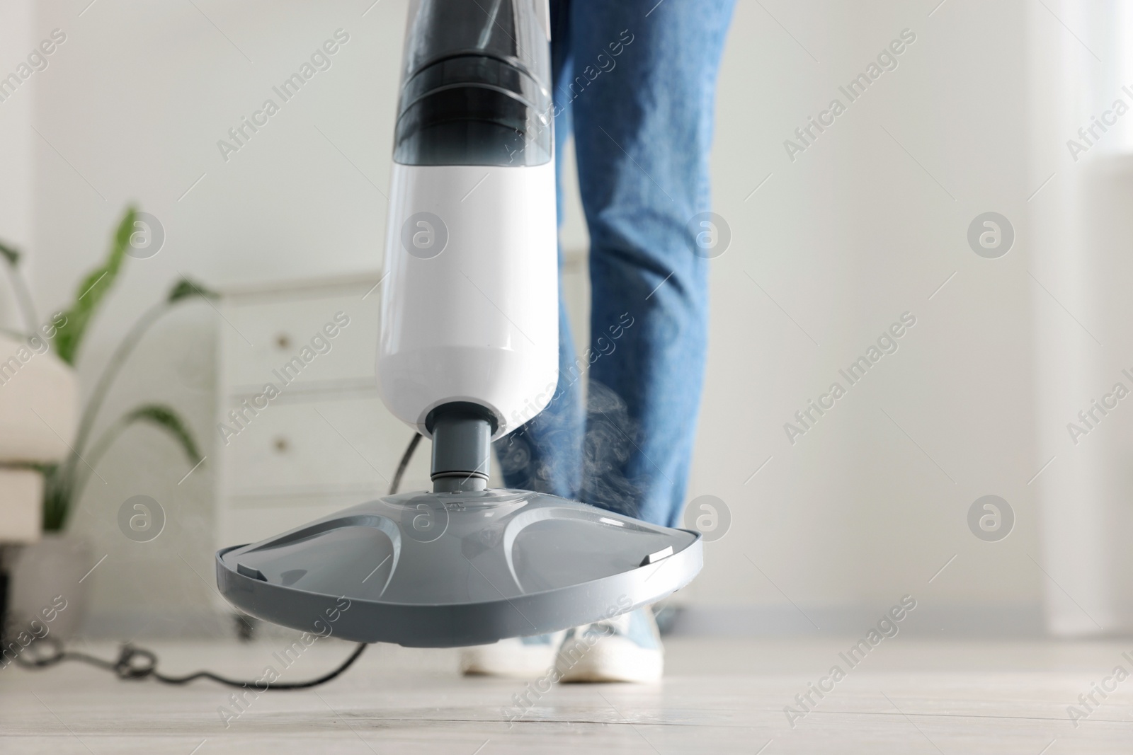 Photo of Woman cleaning floor with steam mop at home, closeup