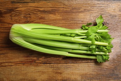Photo of One fresh green celery bunch on wooden table, top view
