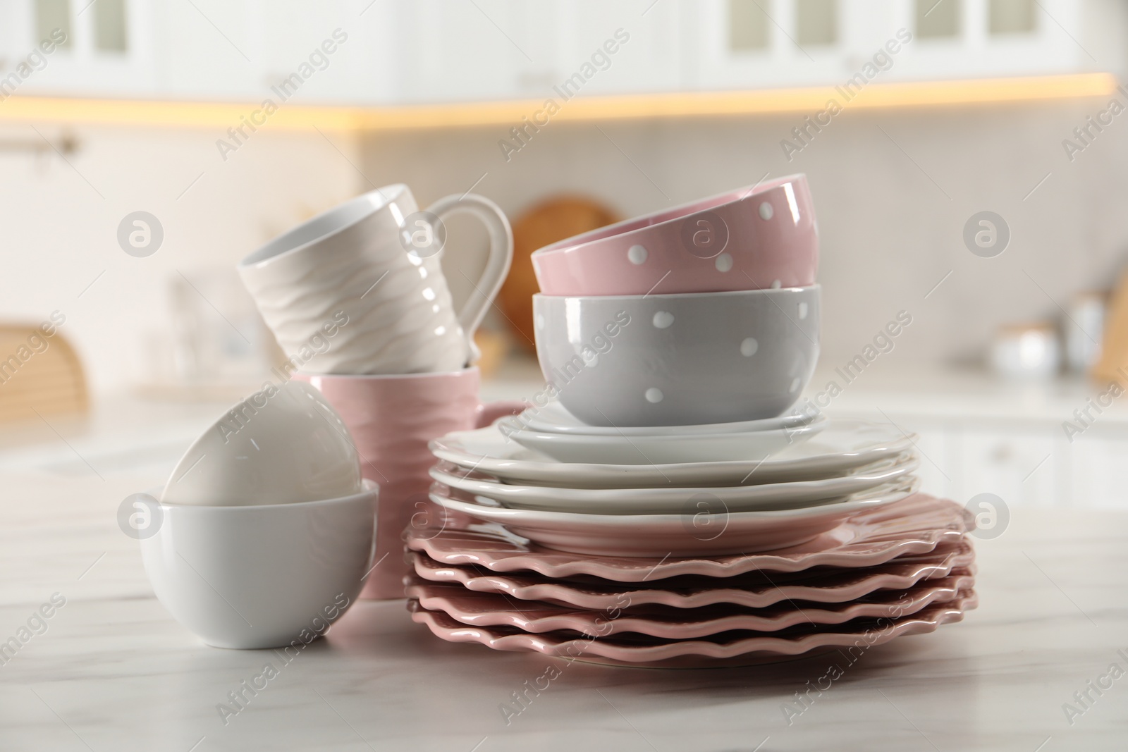 Photo of Many different clean dishware and cups on white marble table in kitchen