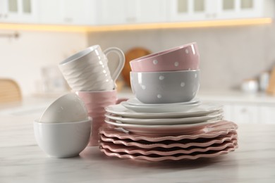 Many different clean dishware and cups on white marble table in kitchen