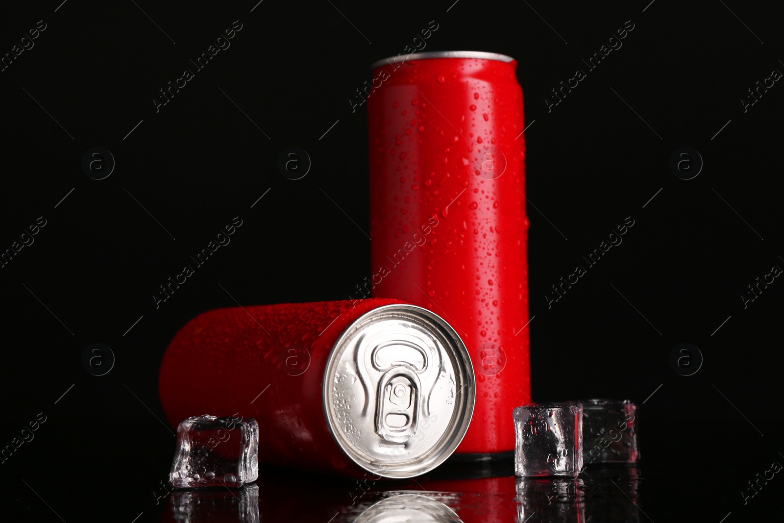 Photo of Energy drinks in wet cans and ice cubes on black background