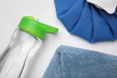 Bottle of water, cold compress and towel on white background, flat lay. Heat stroke treatment