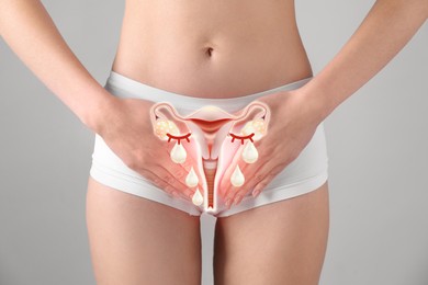 Image of Woman holding hands on her belly and illustration of female reproductive system against light grey background, closeup. Vaginal yeast infection