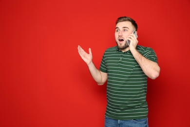 Photo of Portrait of emotional man talking on phone against color background. Space for text