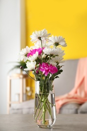 Photo of Beautiful bouquet of Chrysanthemum flowers on grey table indoors. Interior design