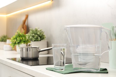 Photo of Water filter jug and glass on white countertop in kitchen