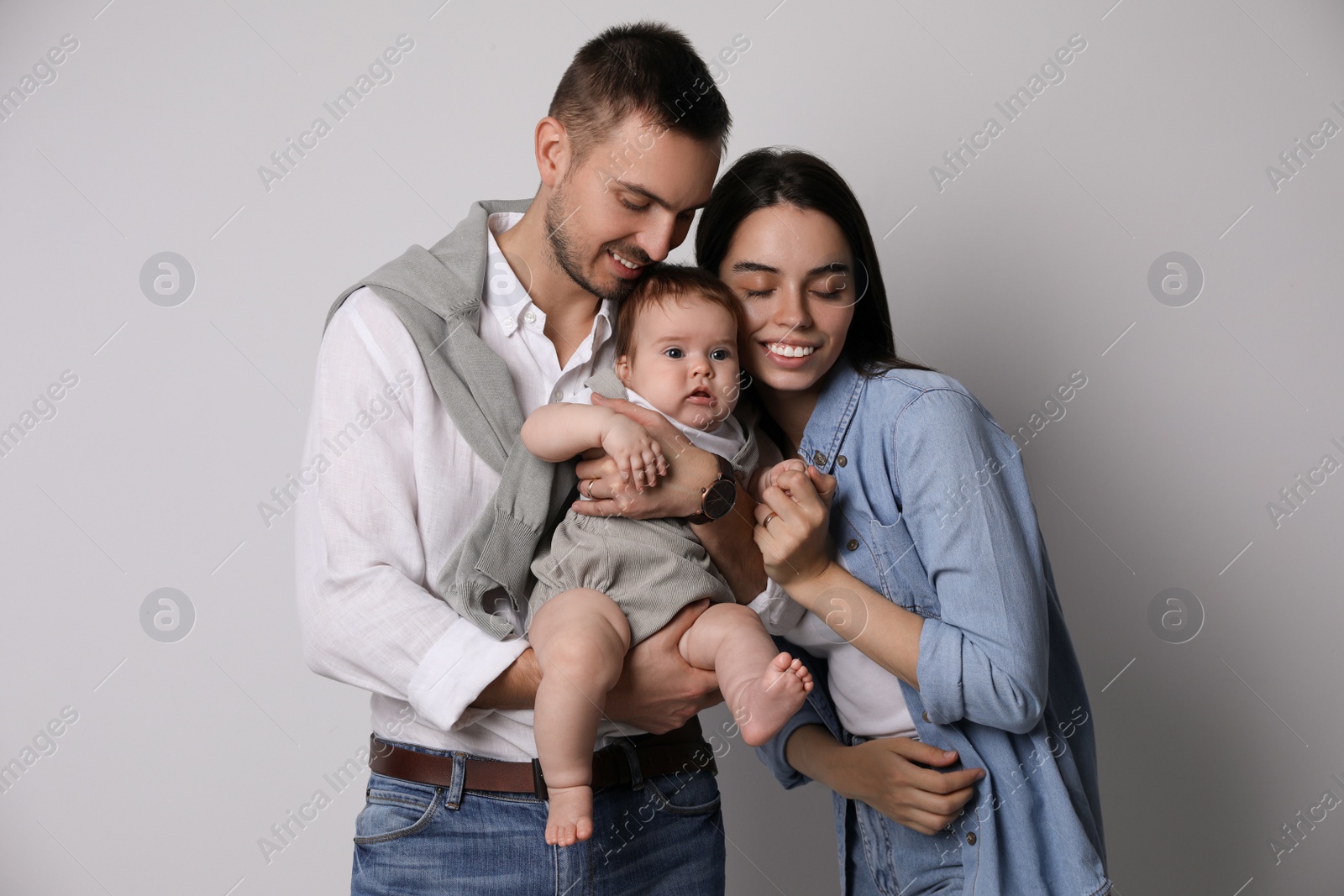 Photo of Happy family. Couple with their cute baby on grey background