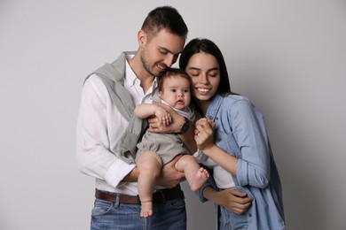 Happy family. Couple with their cute baby on grey background