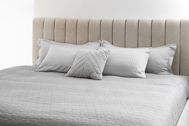 Photo of Many soft pillows on large comfortable bed indoors
