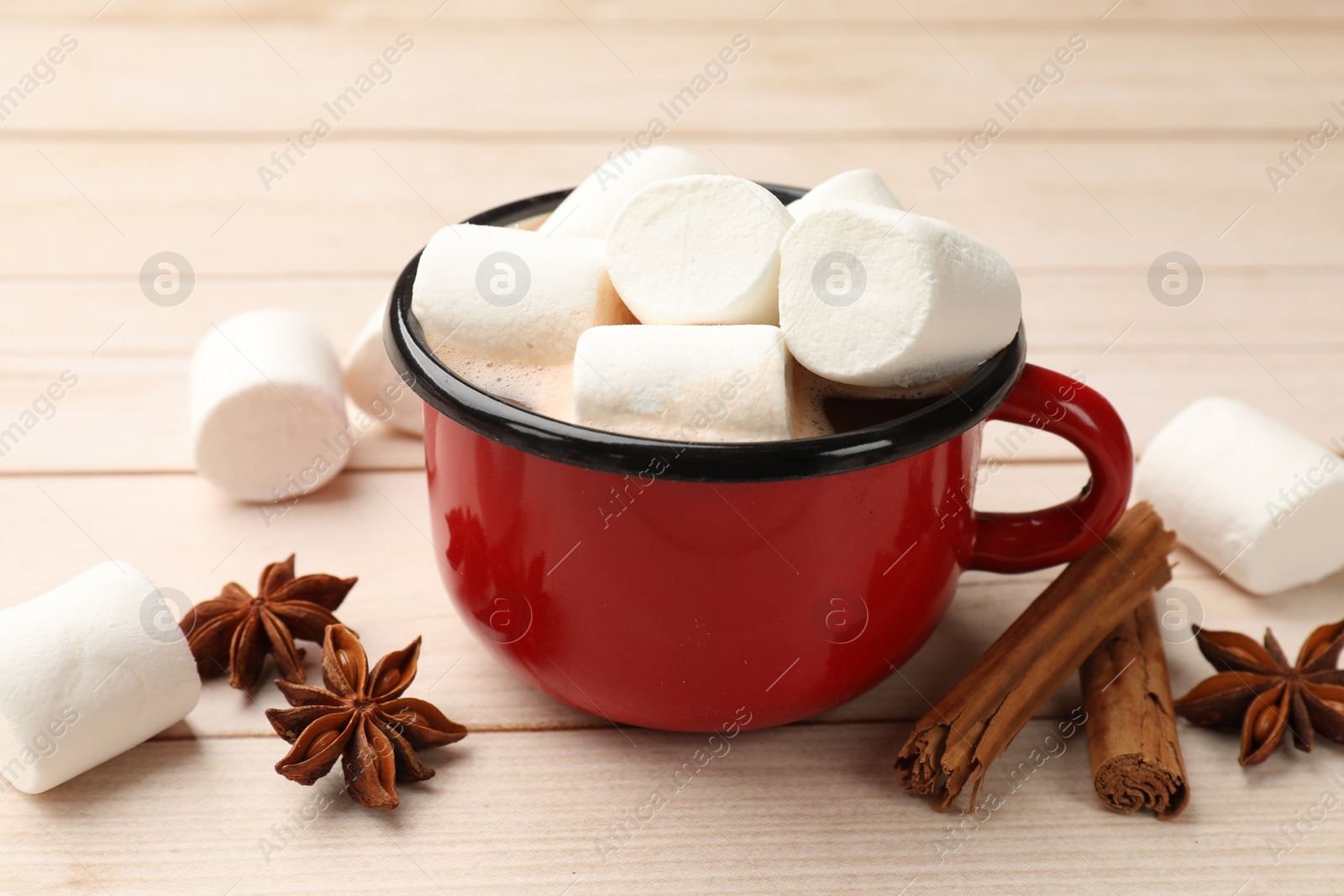 Photo of Tasty hot chocolate with marshmallows and spices on light wooden table, closeup