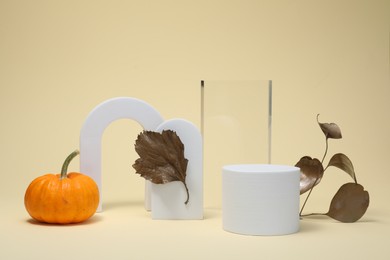 Photo of Autumn presentation for product. Geometric figures, golden leaves and pumpkin on beige background