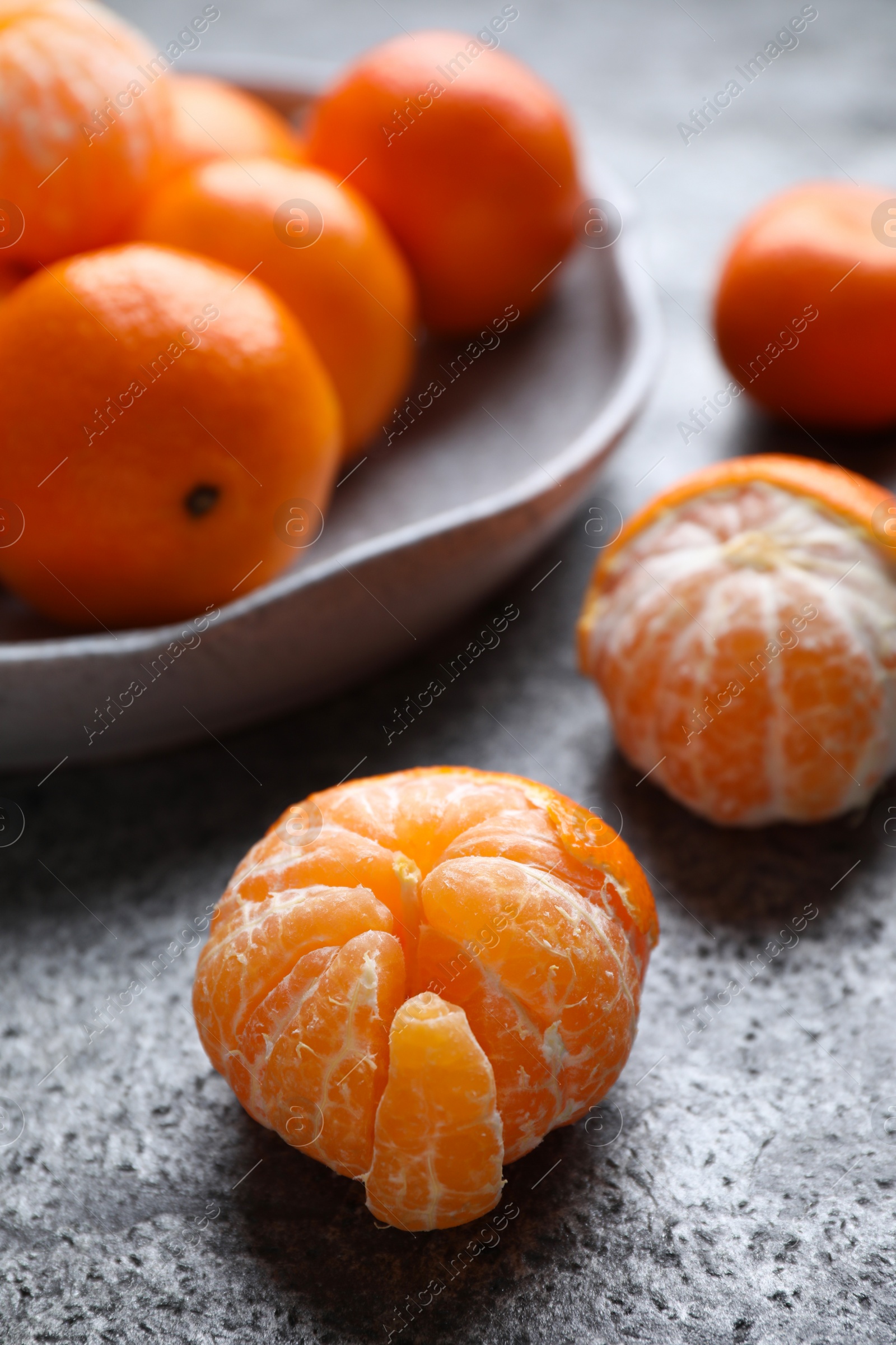 Photo of Peeled ripe tangerine on grey table, closeup