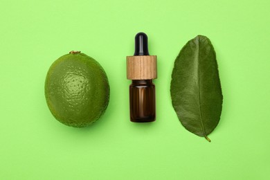 Photo of Bottle of citrus essential oil, fresh lime and leaf on green background, flat lay