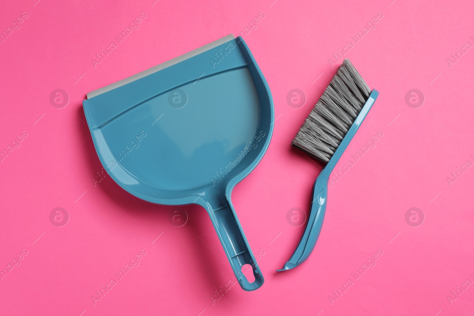 Photo of Plastic hand broom and scoop on pink background, flat lay