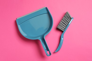 Plastic hand broom and scoop on pink background, flat lay