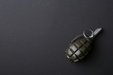 Photo of Hand grenade on black background, top view. Space for text