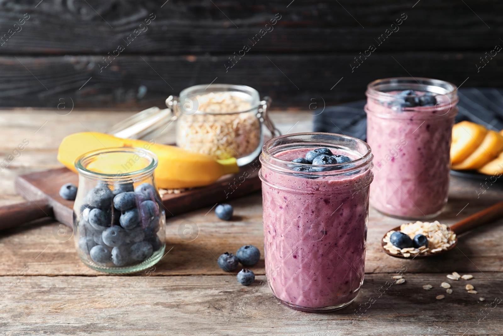 Photo of Jars with blueberry smoothies on wooden table