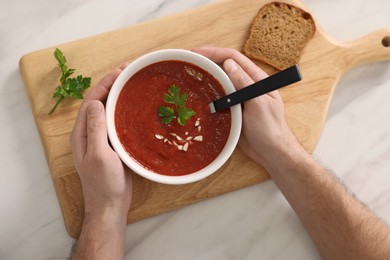 Man with delicious tomato soup at light marble table, top view