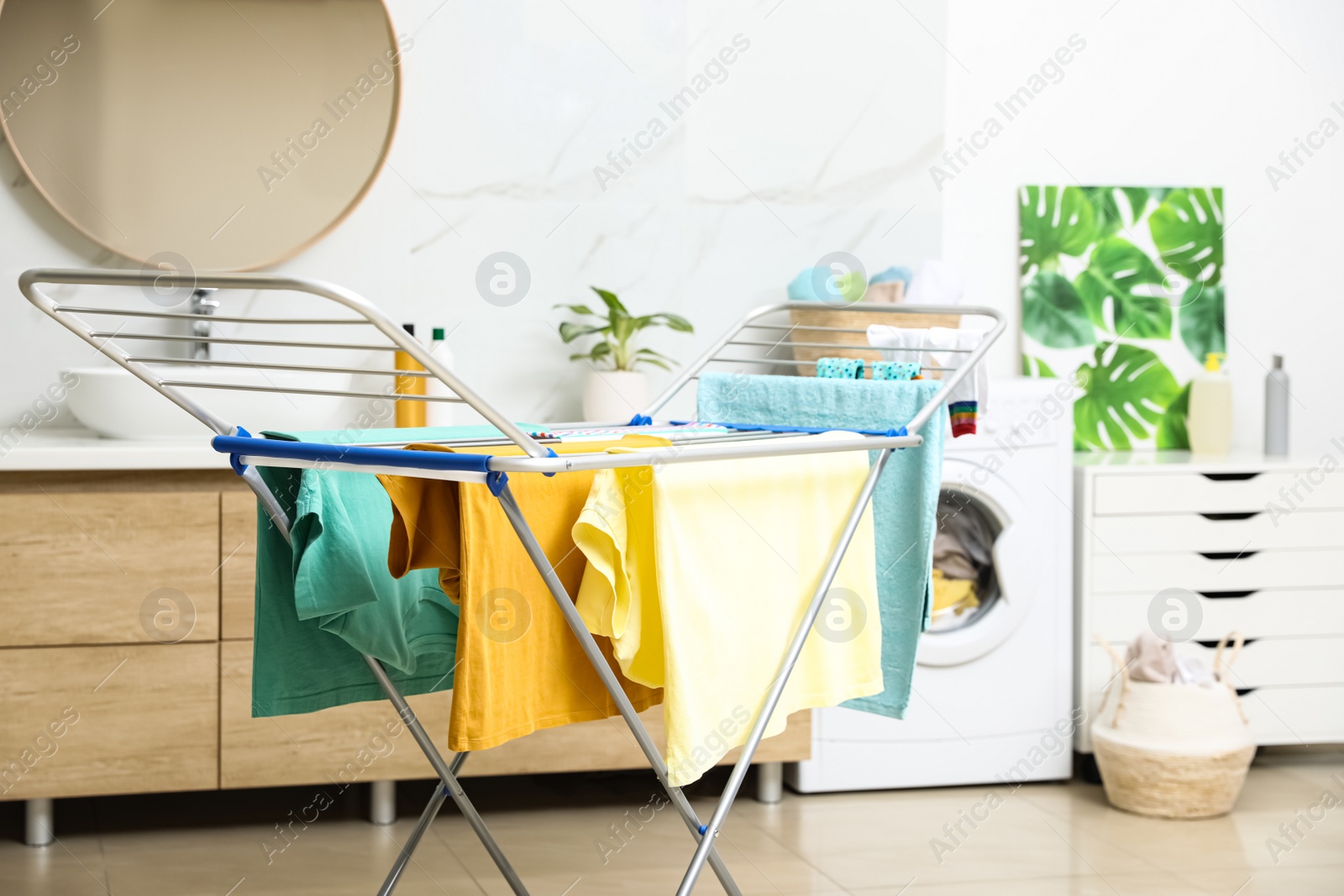 Photo of Clean laundry hanging on drying rack in bathroom