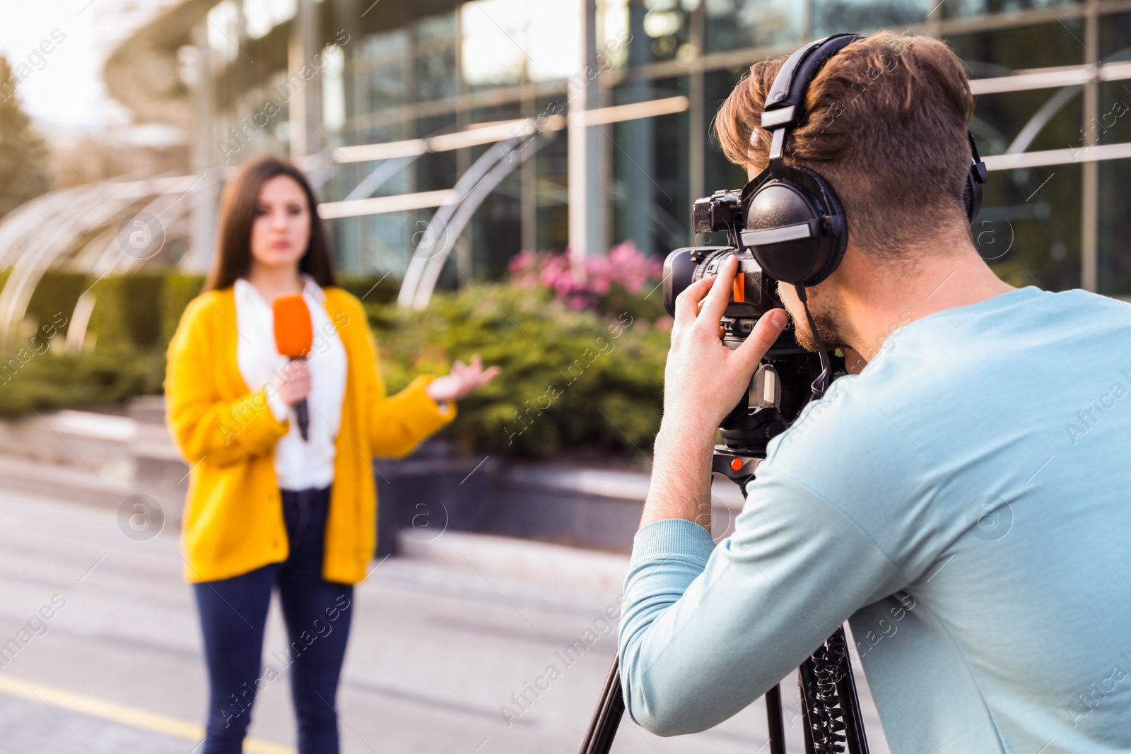 Image of Young journalist and video operator working on city street