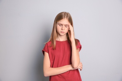 Photo of Teenage girl suffering from headache on grey background