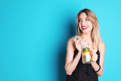 Young woman with mason jar of tasty lemonade on color background. Natural detox drink