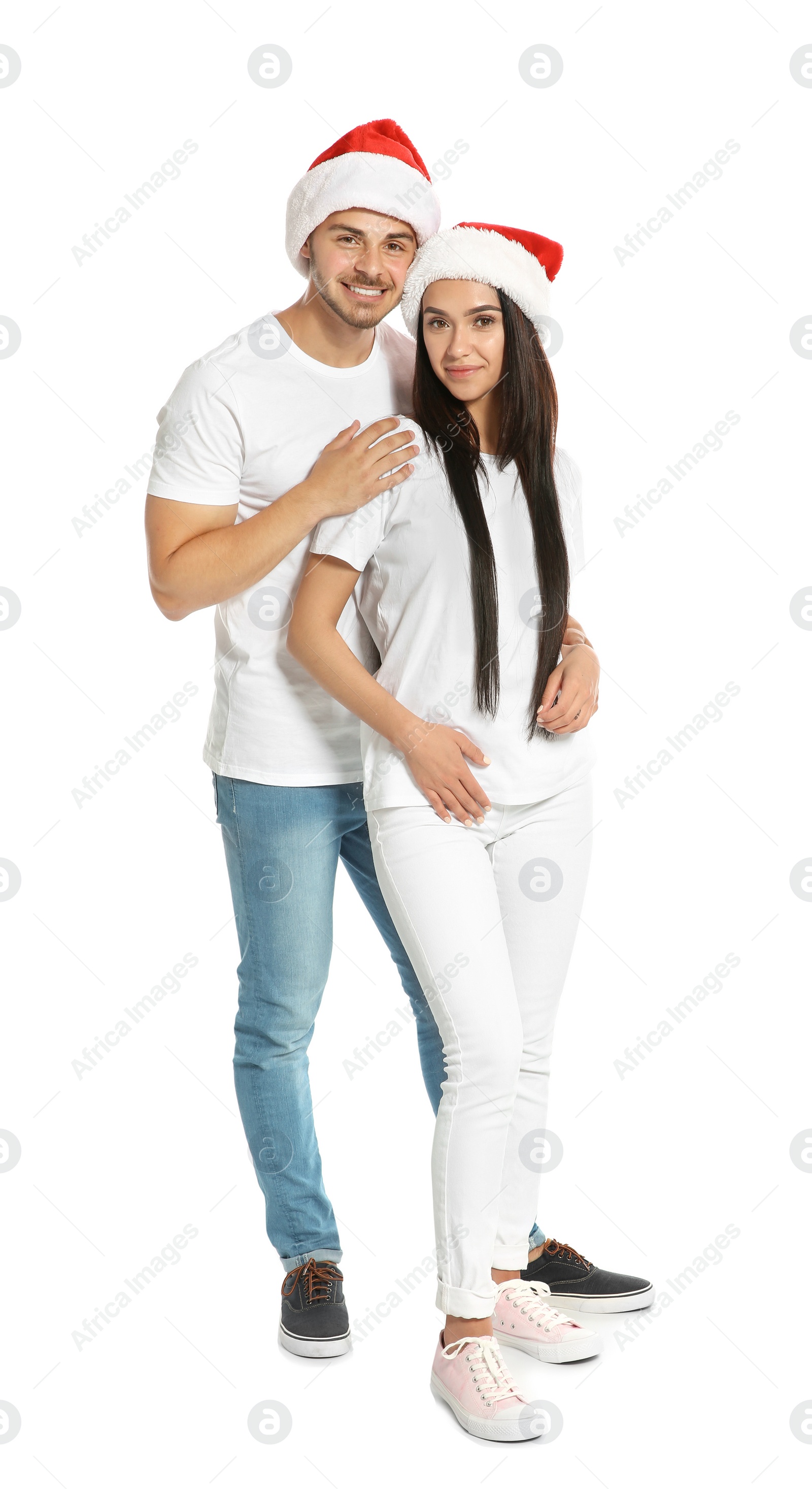 Photo of Young happy couple with Santa hats on white background. Christmas celebration