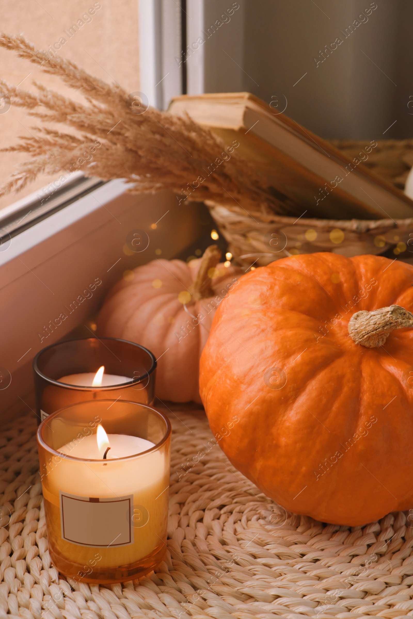 Photo of Scented candles and pumpkins on window sill indoors