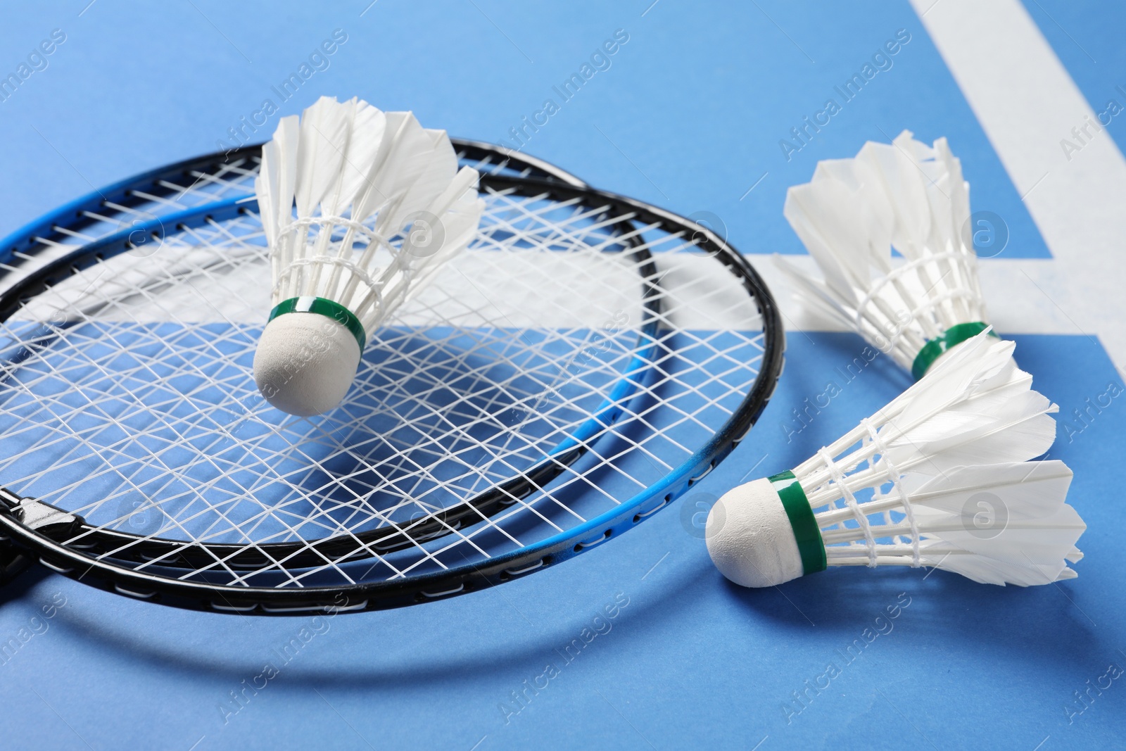 Photo of Feather badminton shuttlecocks and rackets on blue background, closeup