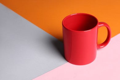 Photo of Red ceramic mug on color background, space for text