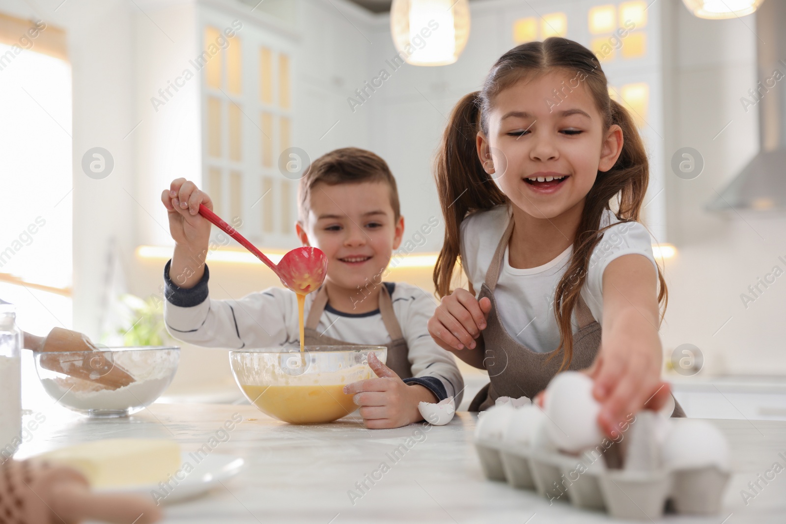 Photo of Cute little children cooking dough together in kitchen