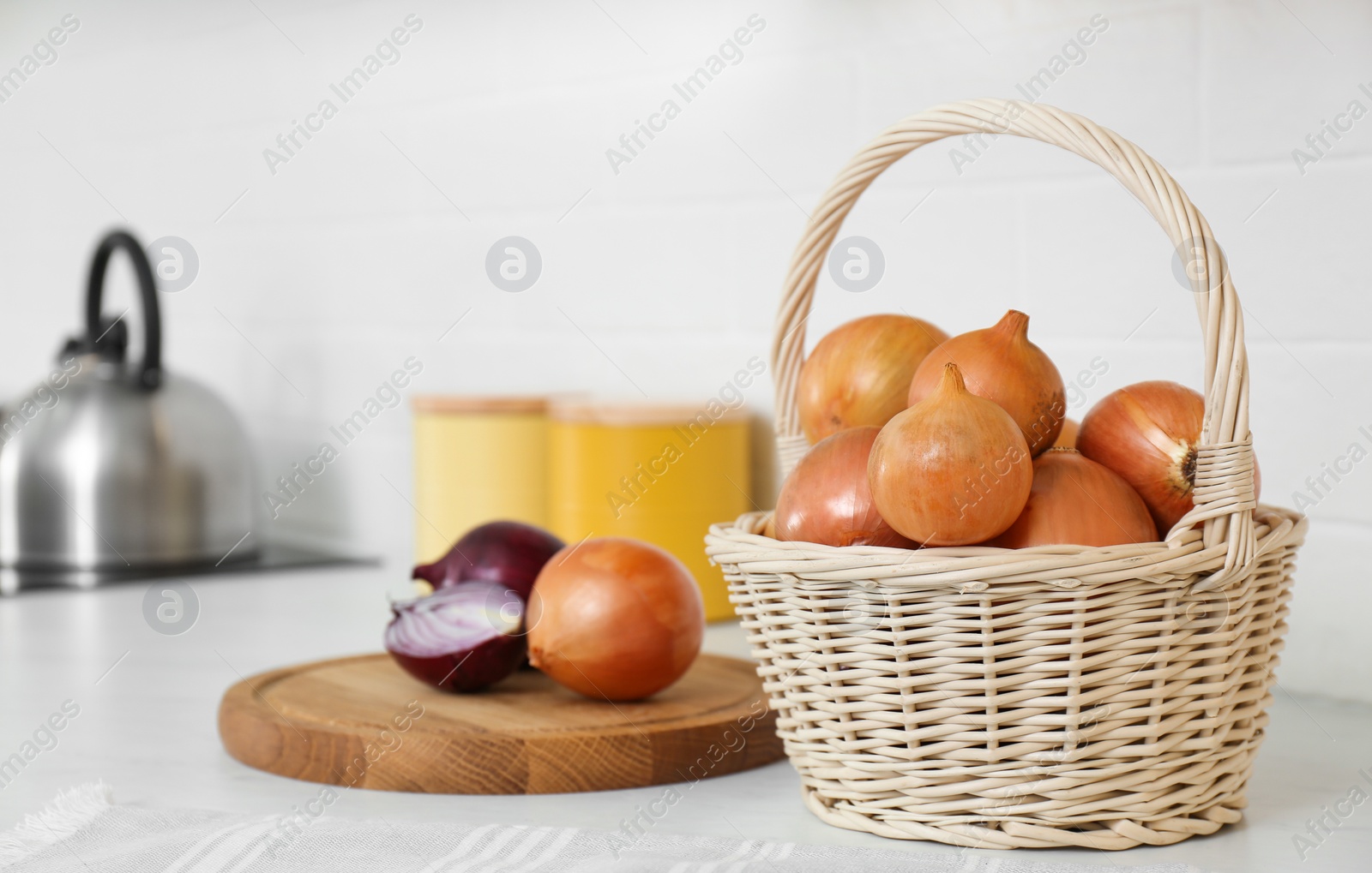 Photo of Fresh cut and whole onions on white countertop in modern kitchen