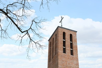 Photo of Brick Christian church against cloudy sky, low angle view
