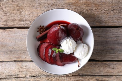Photo of Tasty red wine poached pears and ice cream in bowl on wooden table, top view