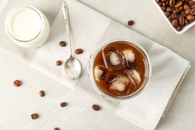 Glass with cold brew coffee and beans on light background, top view