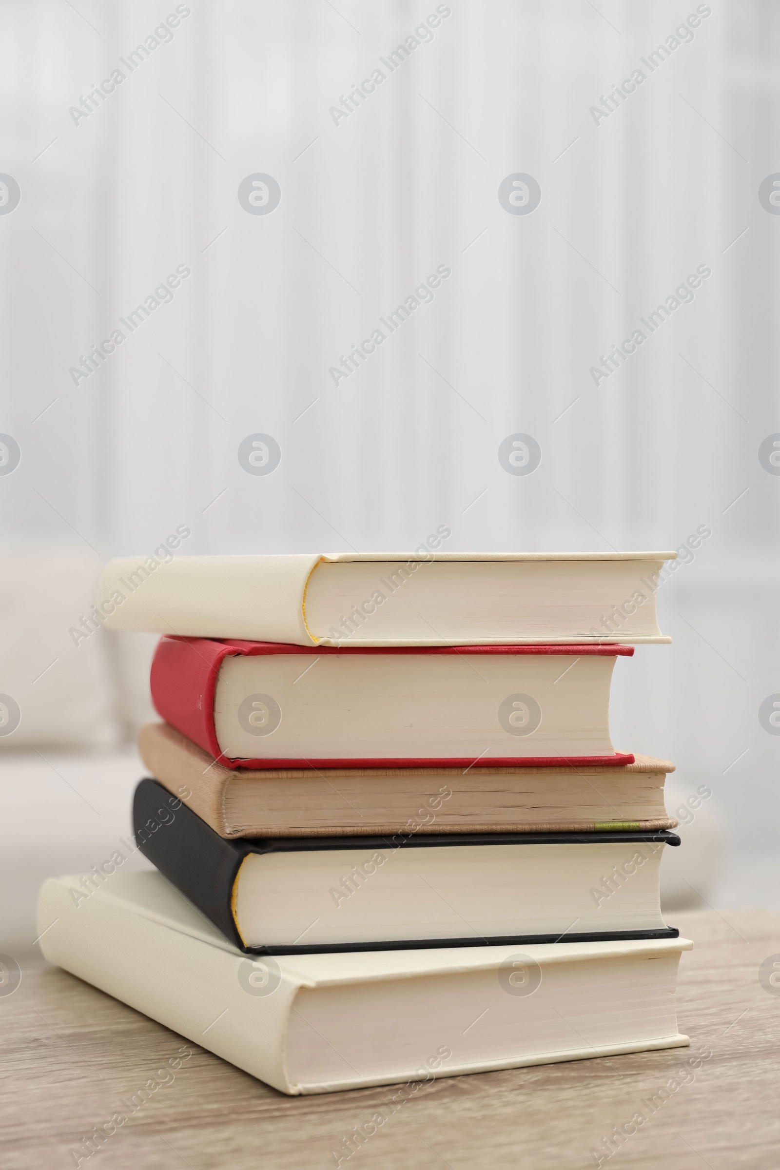 Photo of Stack of hardcover books on wooden table indoors