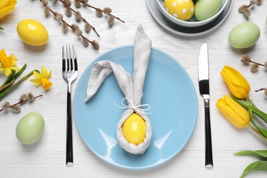 Festive Easter table setting with eggs on white wooden background, flat lay